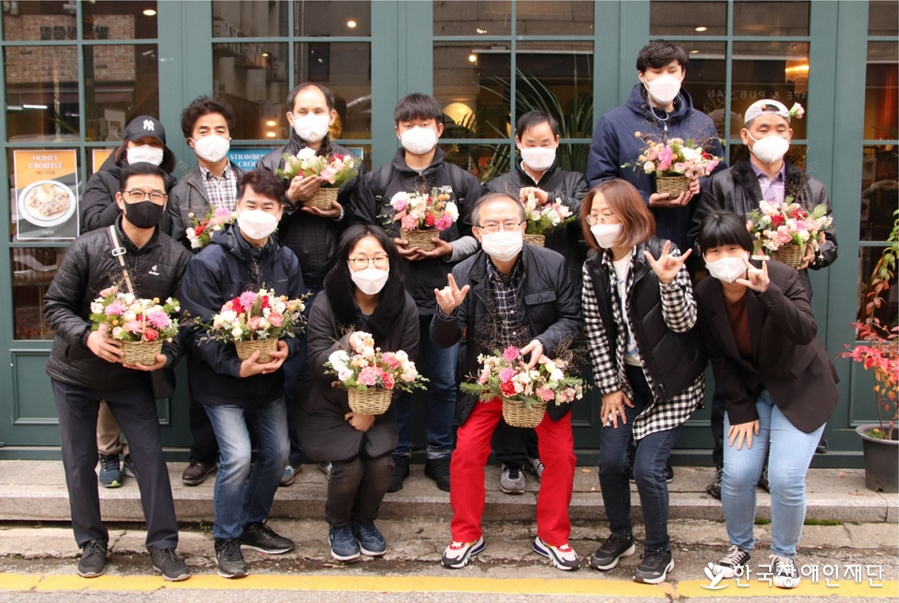  꽃꽂이 수업을 마친 손잡다 회원들이 각자 완성한 꽃바구니를 들고 사진을 찍고 있다. 