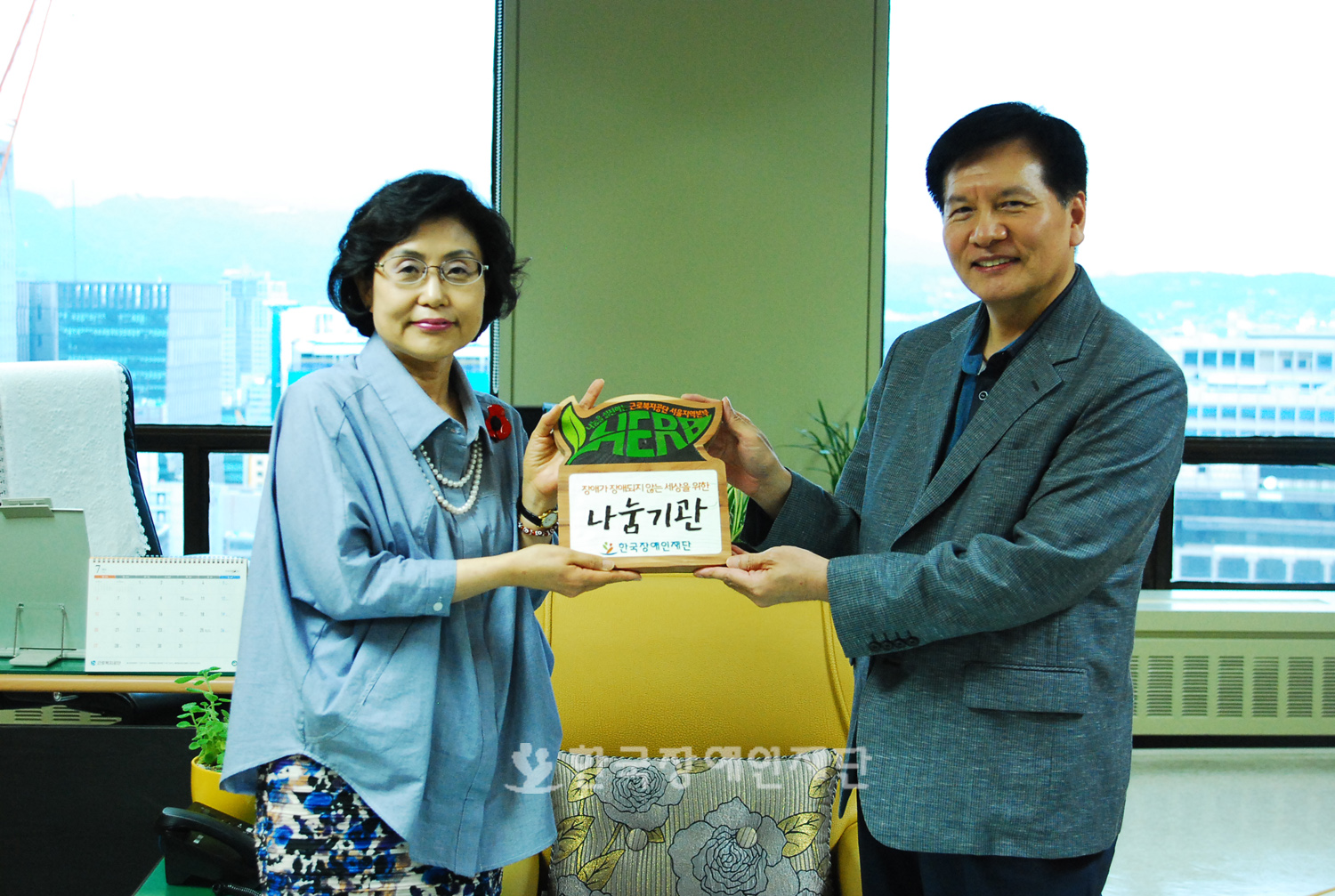 한국장애인재단 이채필 이사장(오른쪽)이 근로복지공단 서울지역본부 윤영순 본부장(왼쪽)에게 나눔기관 현판을 전달하고 있는 사진